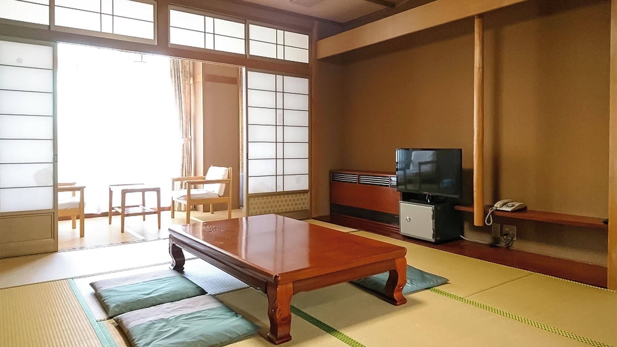 Habitació japonesa tradicional amb sòl de tatami, una taula de fusta baixa, una televisió i un petit armari.