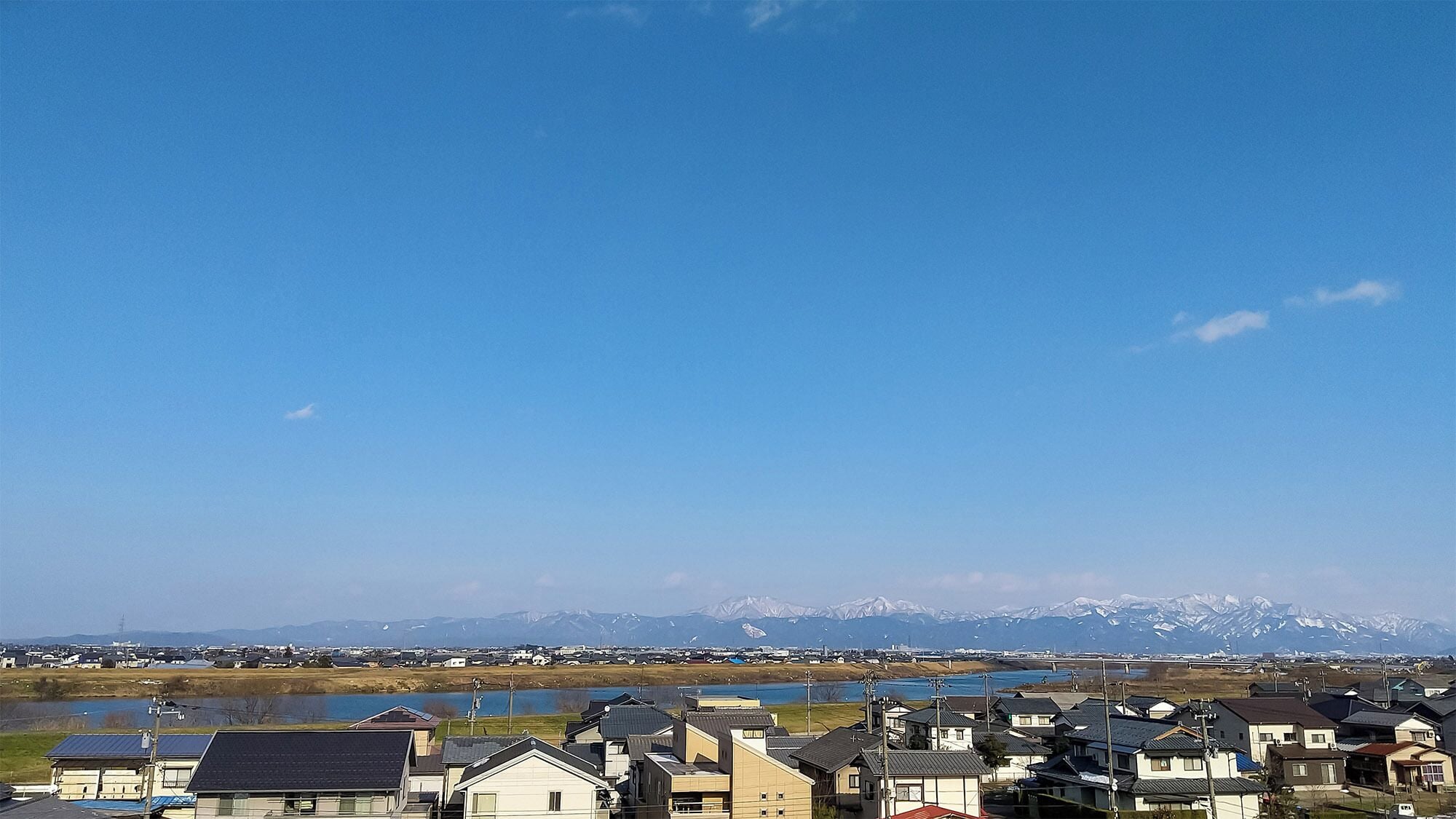 A residential area with houses, a lake, and mountains in the background.