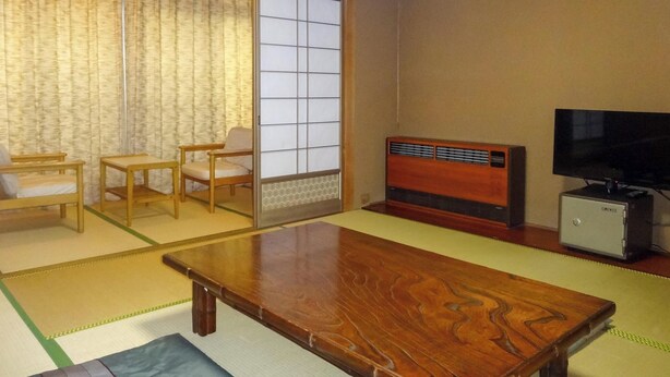 A traditional Japanese room with tatami flooring, a low wooden table, a television, and a small cabinet. - Daionji Onsen Banshokaku (Fukui)
