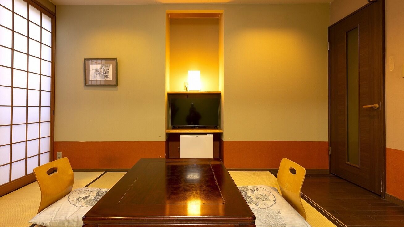 Ein traditioneller japanischer Raum mit Tatami-Böden, einem niedrigen Tisch und verschiebbaren Türen.