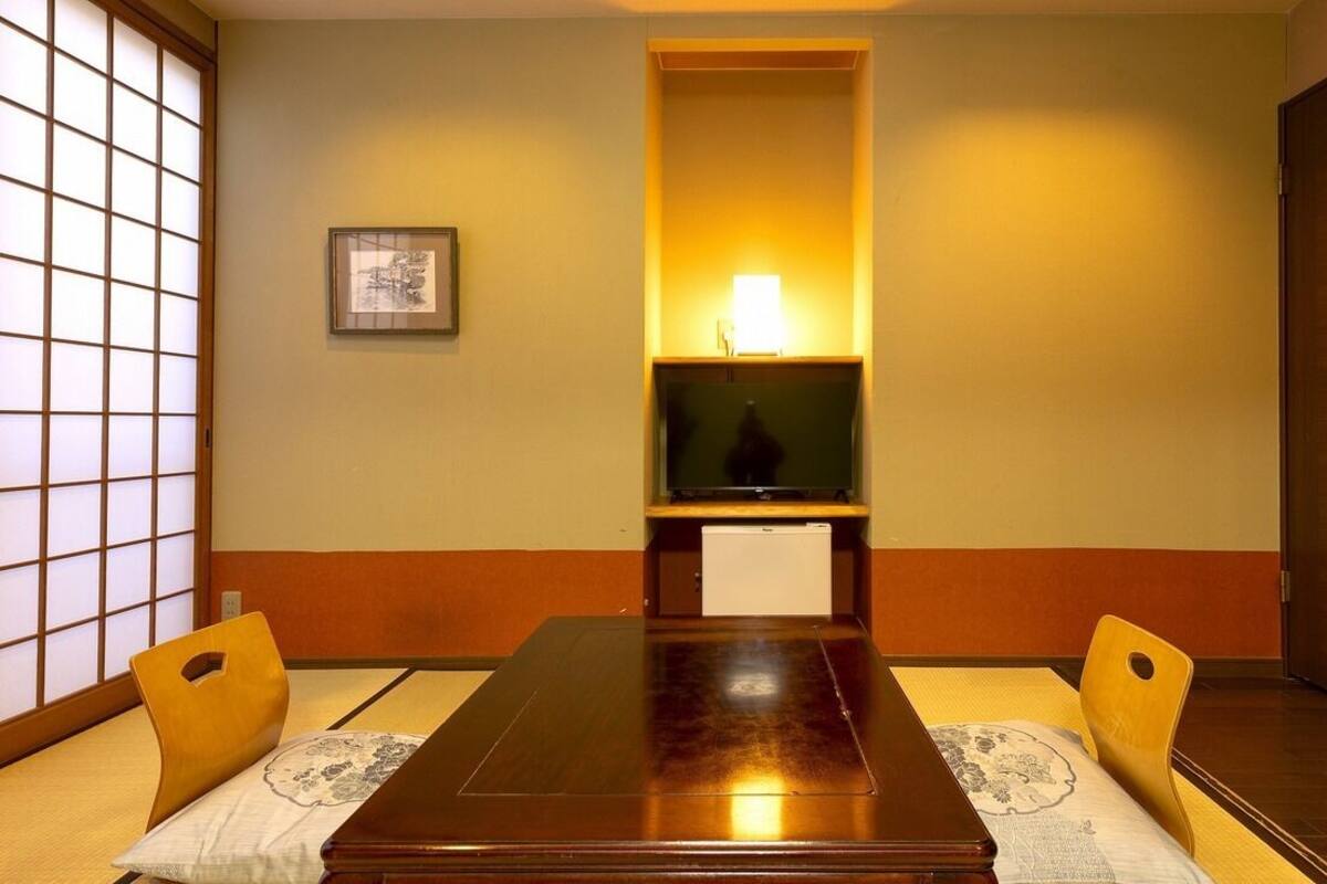 A traditional Japanese room with tatami flooring, a low table, and sliding doors.
