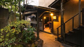 Un edificio japonés tradicional con una escalera de madera y un camino de piedra que lleva a una entrada.