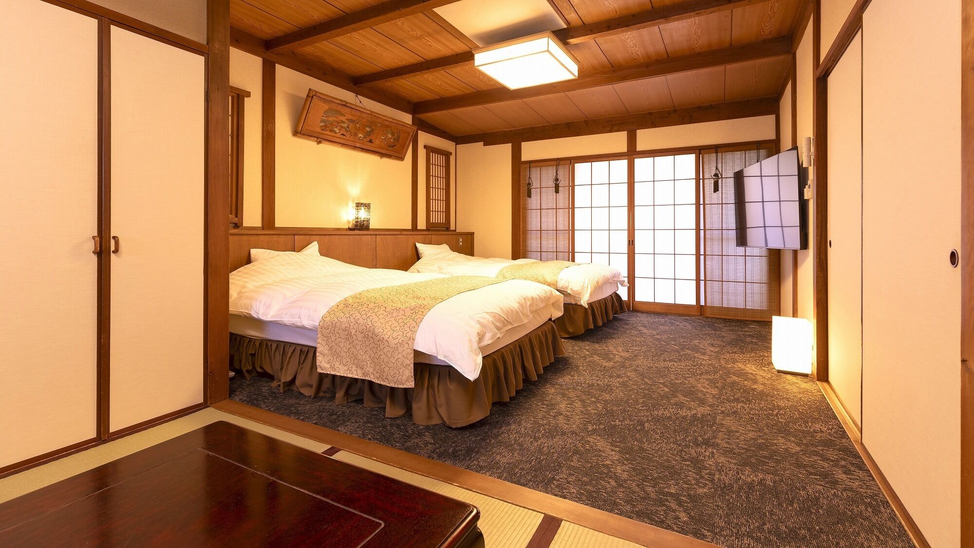 Ein traditionelles Hotelzimmer im japanischen Stil mit Holzbalkendecke, Tatami-Böden und Shoji-Schiebetüren.