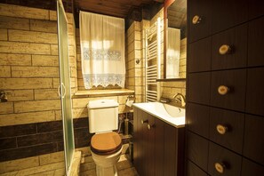 Bathroom features a toilet, sink, shower, and wooden cabinet.