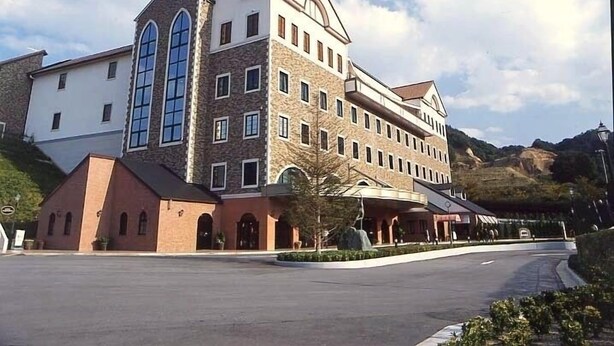 A large, multi-story building with a prominent arched window and a steeply pitched roof. - Imabari Plaza Hotel (Imabari)