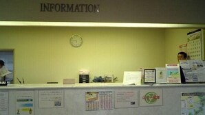 A reception desk with a clock, informational posters, and a sign labeled "INFORMATION" above. - Imabari Plaza Hotel (Imabari)