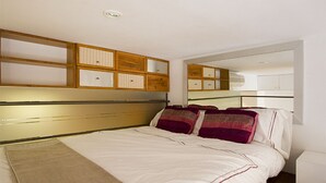Ein Schlafzimmer mit Bett, Holz-Kopfteil, eingebauten Schränken und einem Spiegel.