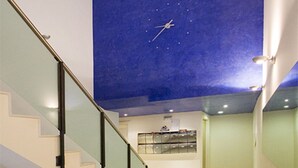 Ein modernes Interieur mit einer Treppe, einem Deckenfresko und einer Rezeption.