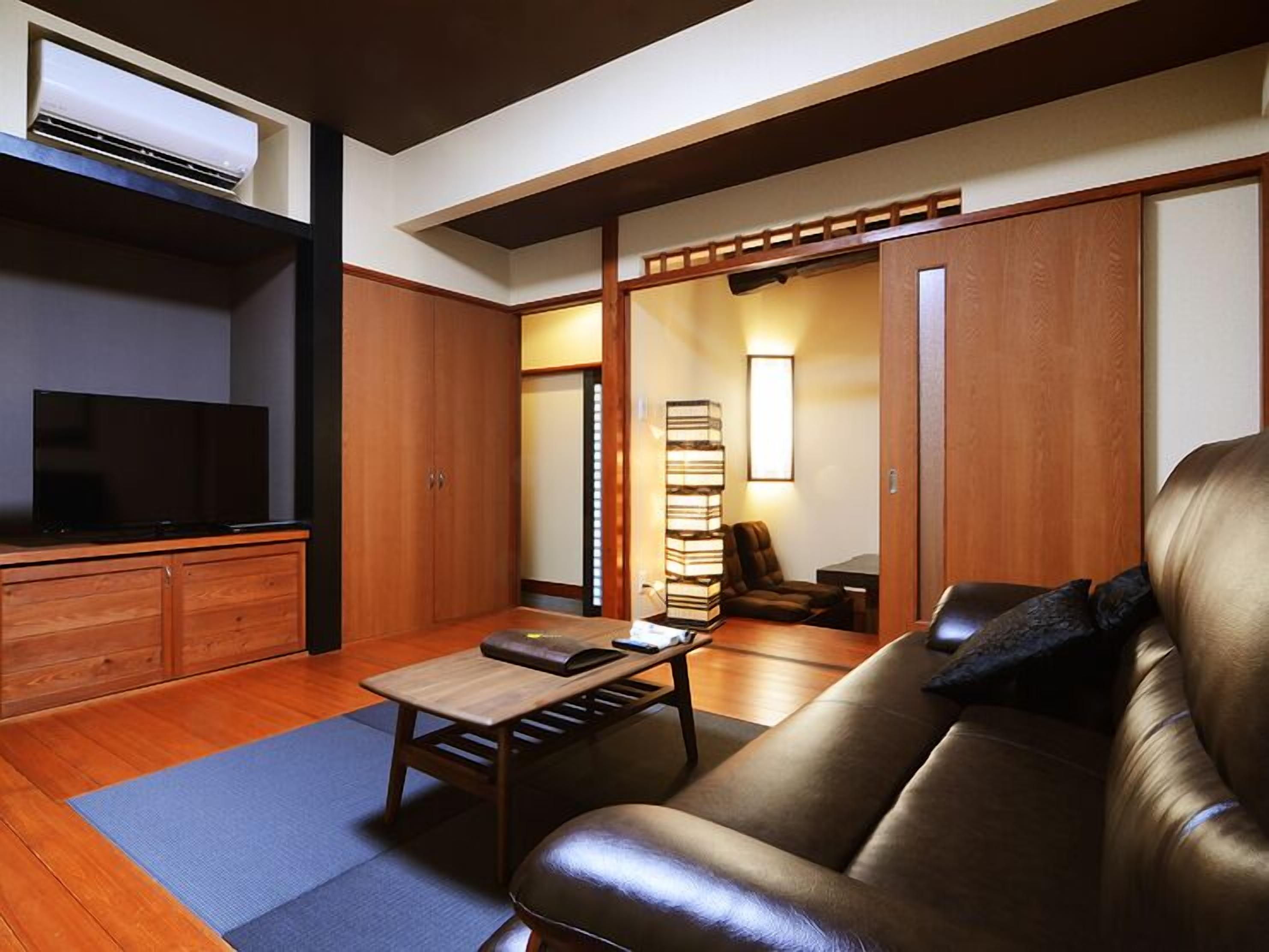 A living room with a leather sofa, a TV, a coffee table, and a bookshelf.
