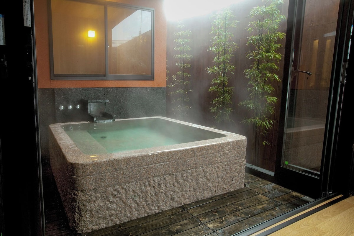 A spa room with a hot tub, a wooden floor, and a glass door leading outside.