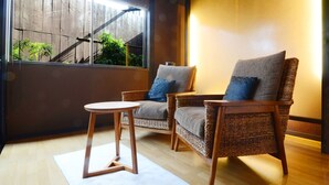 A room with two wicker chairs, a small round table, and a view of a wooden staircase and greenery outside. - Tokunoyado Fubuan (Beppu)