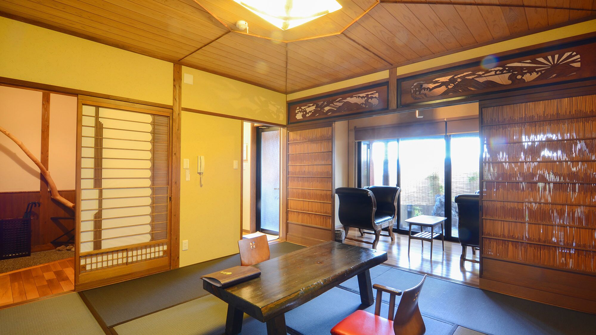 A traditional Japanese room with tatami flooring, sliding doors, and a low table with chairs.