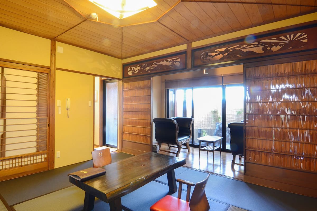 A traditional Japanese room with tatami flooring, sliding doors, and a low table with chairs.