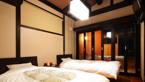 A hotel room with two beds, a sliding glass door to the outside, and a ceiling light. - Tokunoyado Fubuan (Beppu)