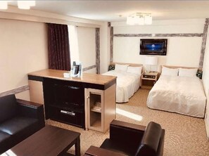 Ein Hotelzimmer mit Schreibtisch, zwei Betten, Fernseher und einer Minibar.