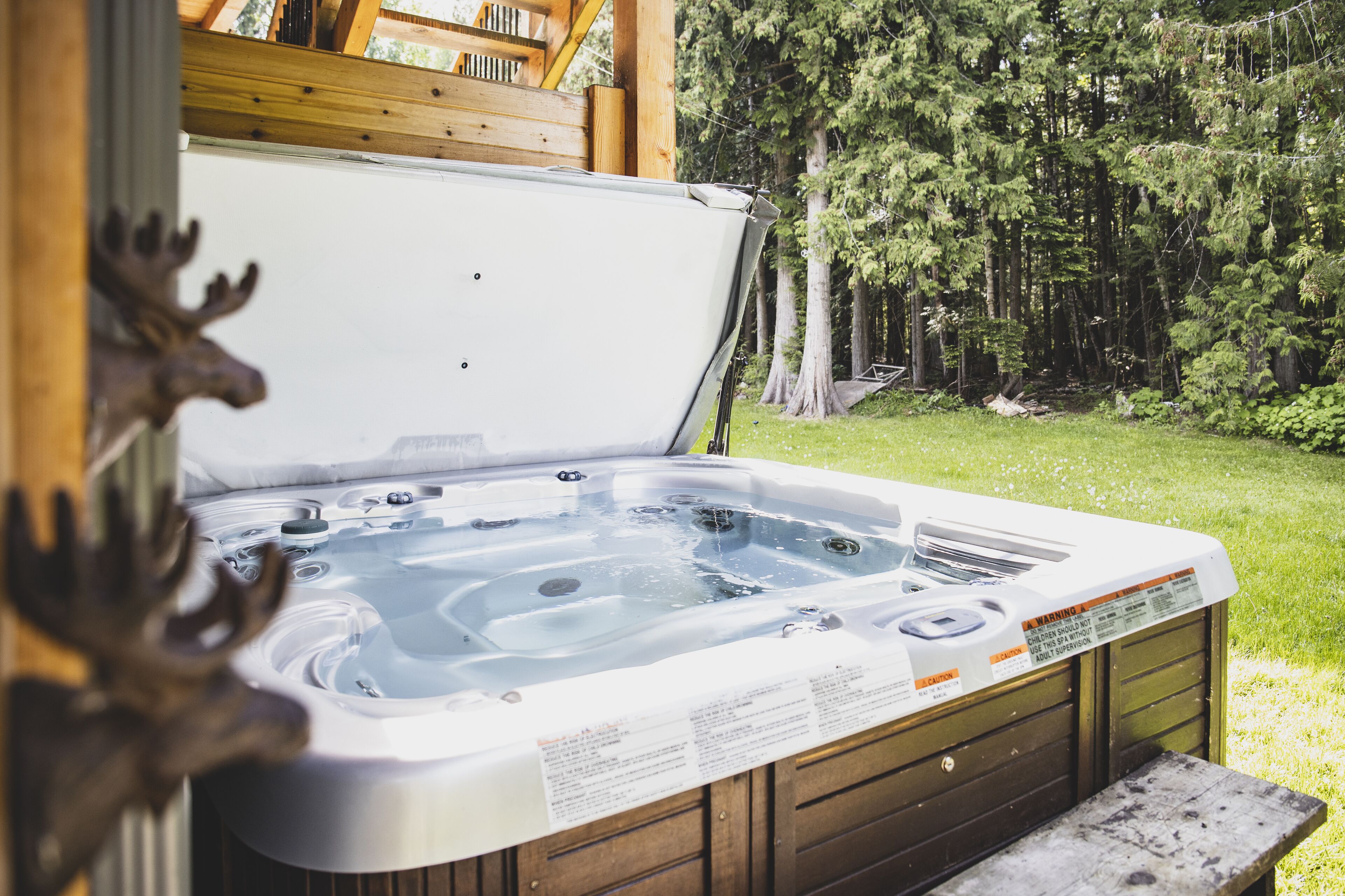 Un bain à remous avec une terrasse en bois et une forêt en arrière-plan.