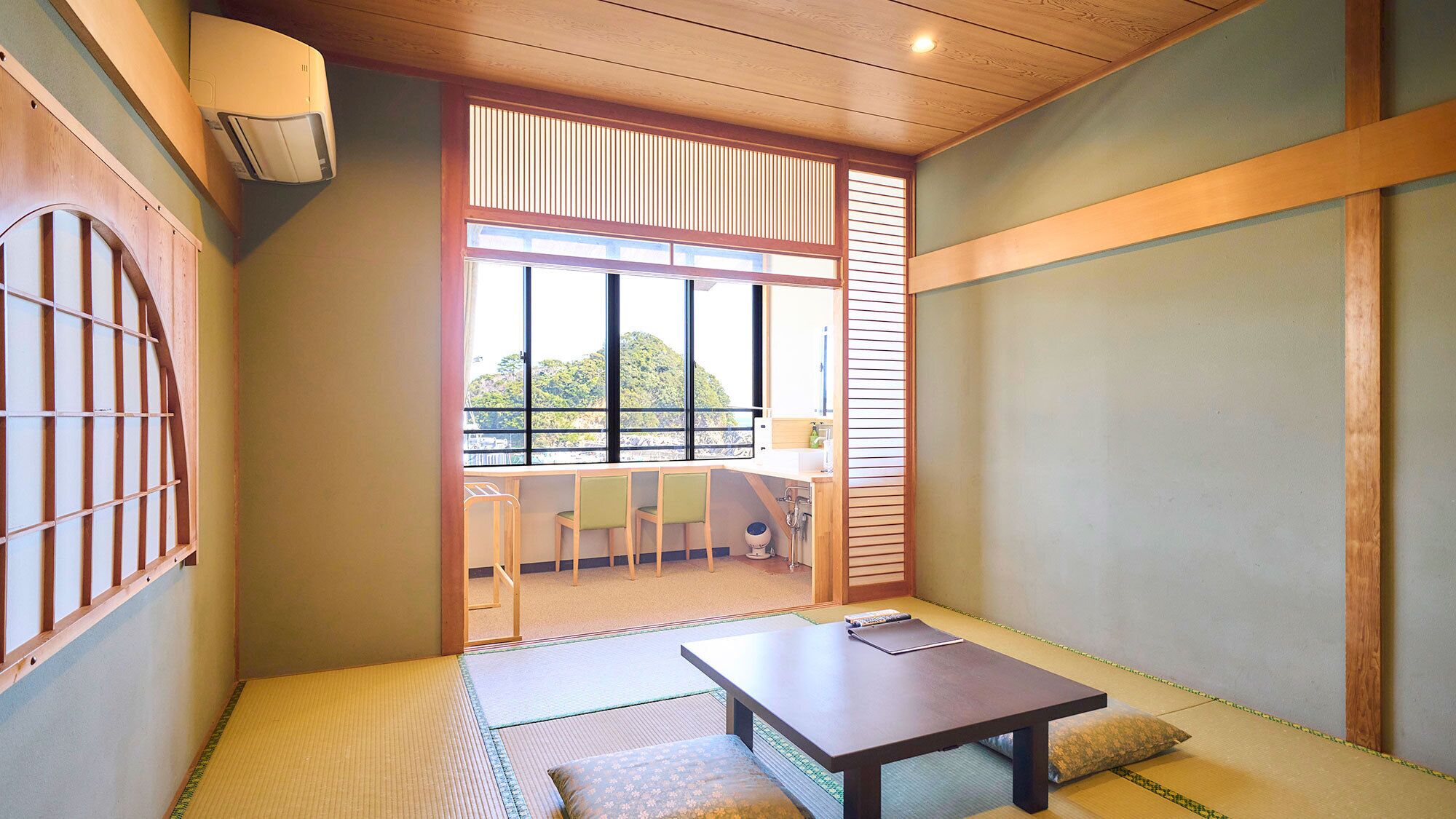 A traditional Japanese room with tatami flooring, a low table, and a sliding door leading to a balcony.