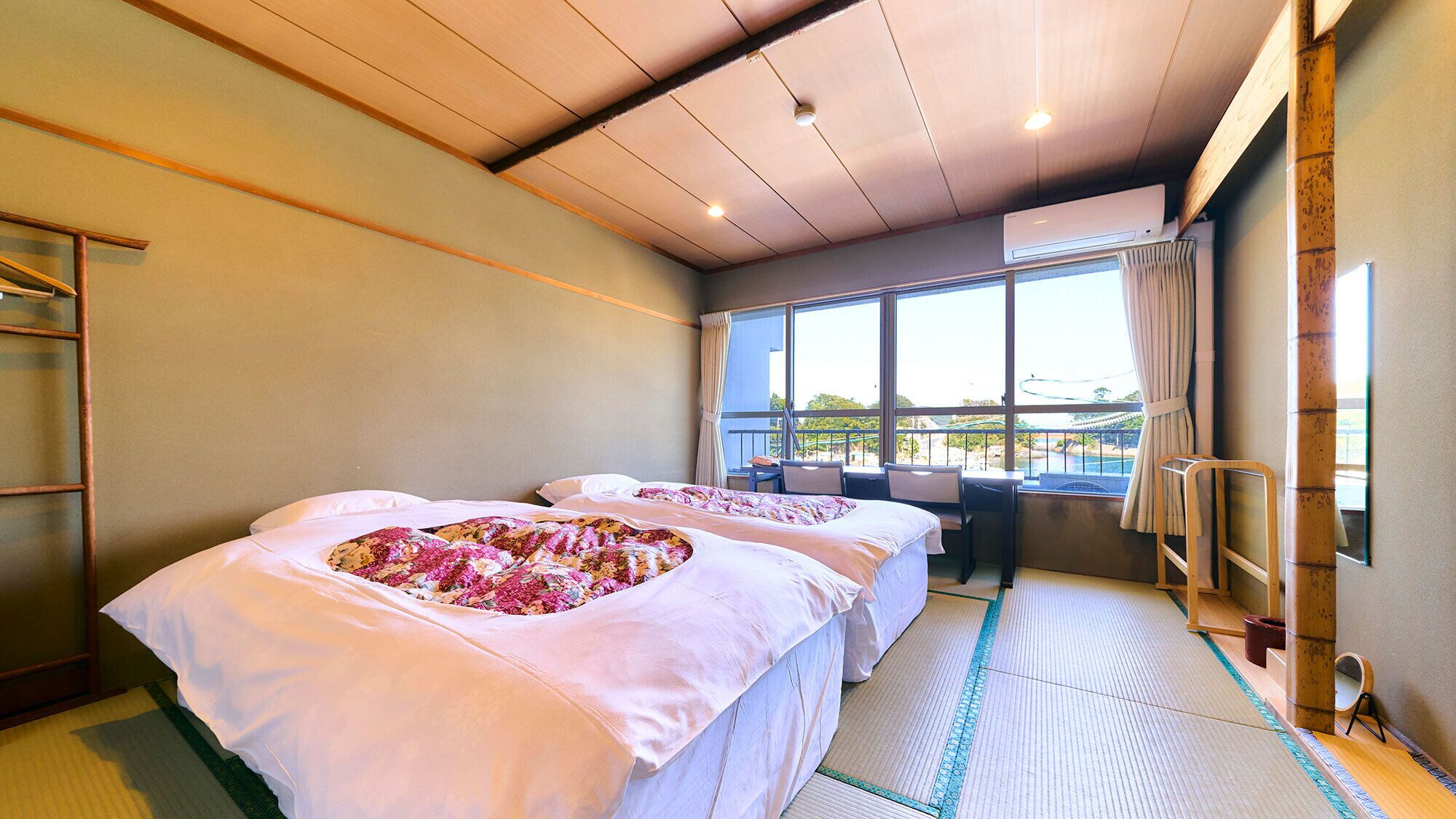 A hotel room with two beds, a balcony, and a view of the outdoors.
