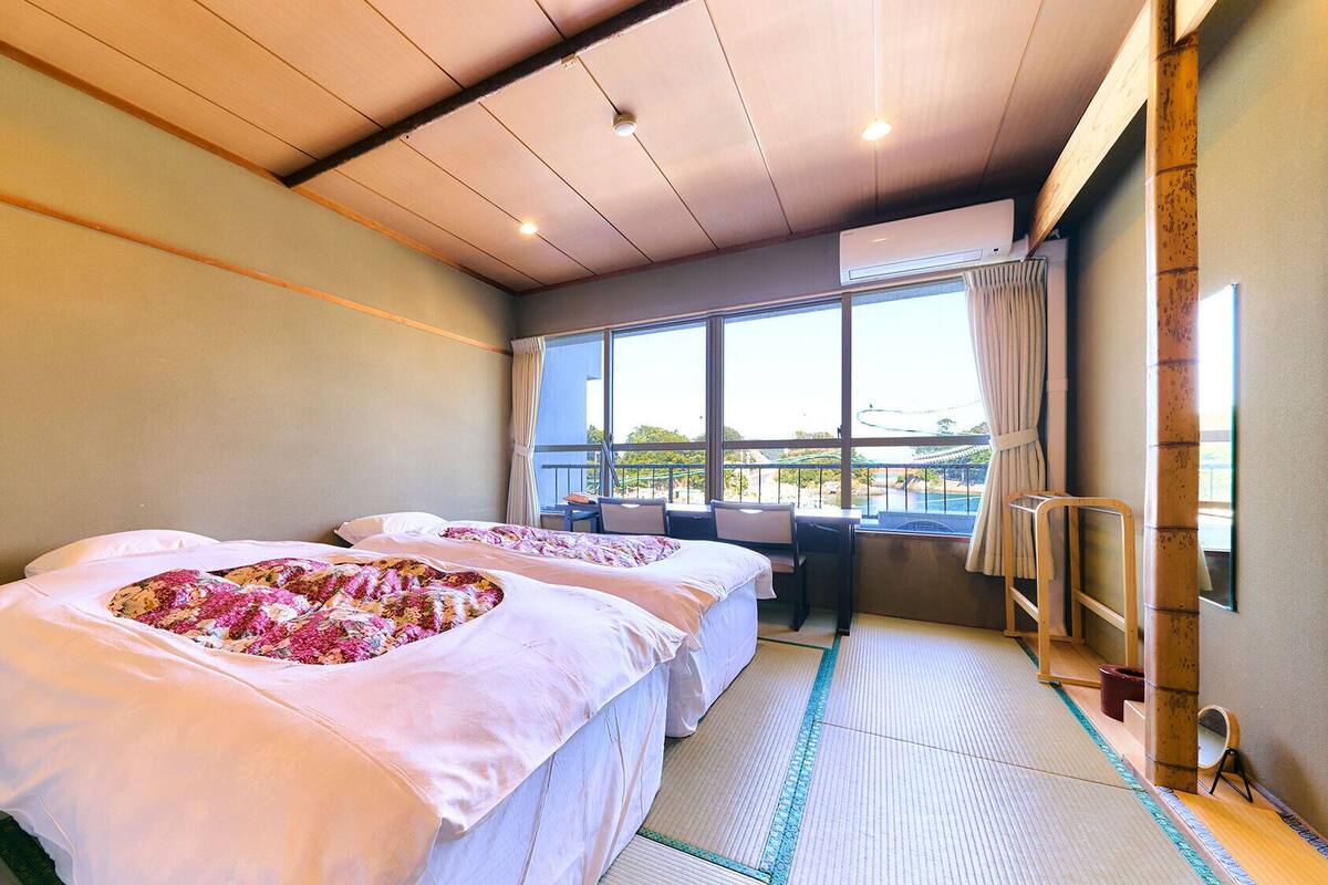 Ein Hotelzimmer mit zwei Betten, einem Balkon und Blick ins Freie.
