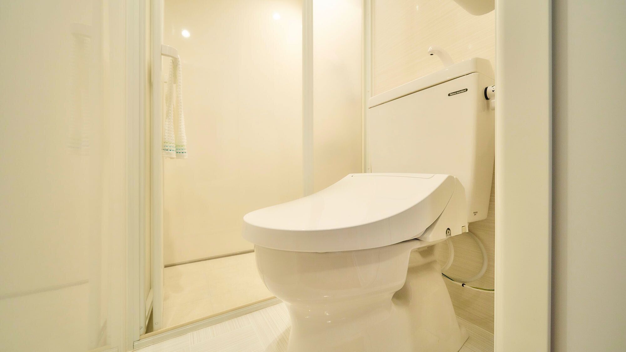 A white toilet in a bathroom with a glass shower door and a white towel rack.