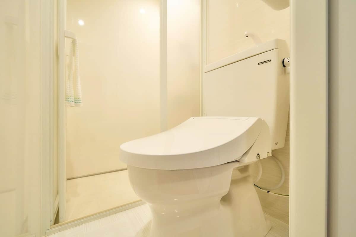 A white toilet in a bathroom with a glass shower door and a white towel rack.