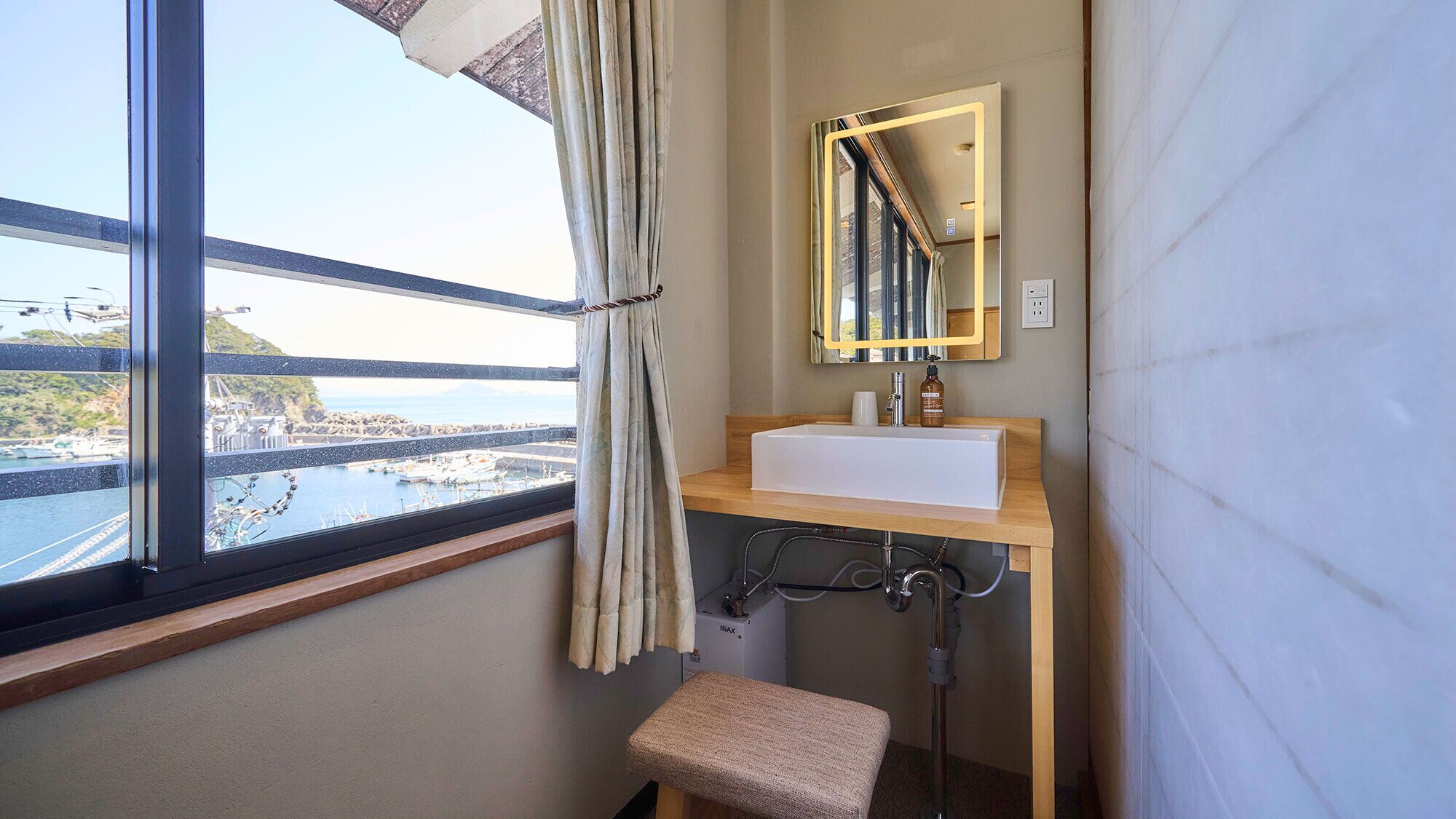 A bathroom with a window, a sink, a mirror, and a shower.