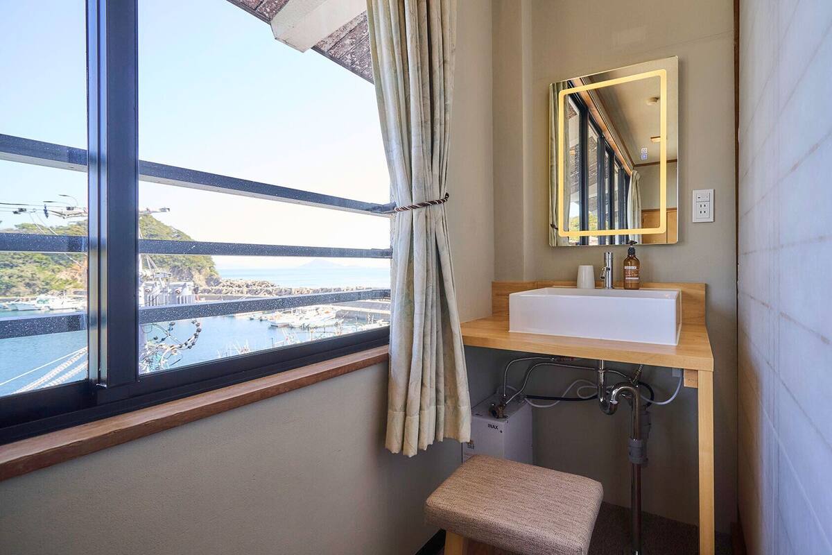 Ein Badezimmer mit Fenster, Waschbecken, Spiegel und Dusche.