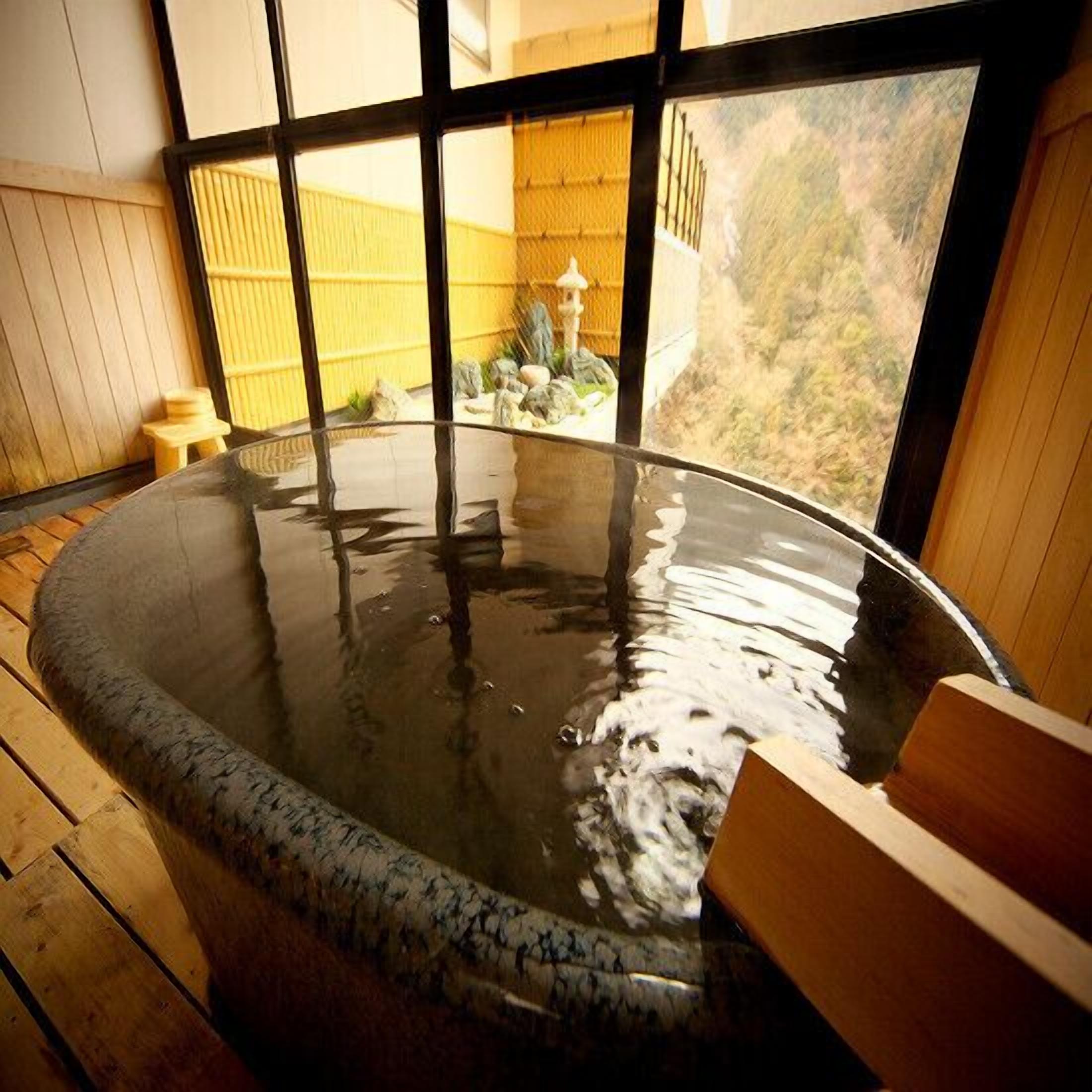 Un bain à remous avec un intérieur en bois et une vue sur un paysage montagneux grâce à de grandes fenêtres.