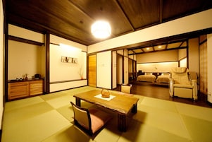 Una habitación japonesa tradicional con suelo de tatami, una mesa de madera baja, un banco acolchado y un sofá.