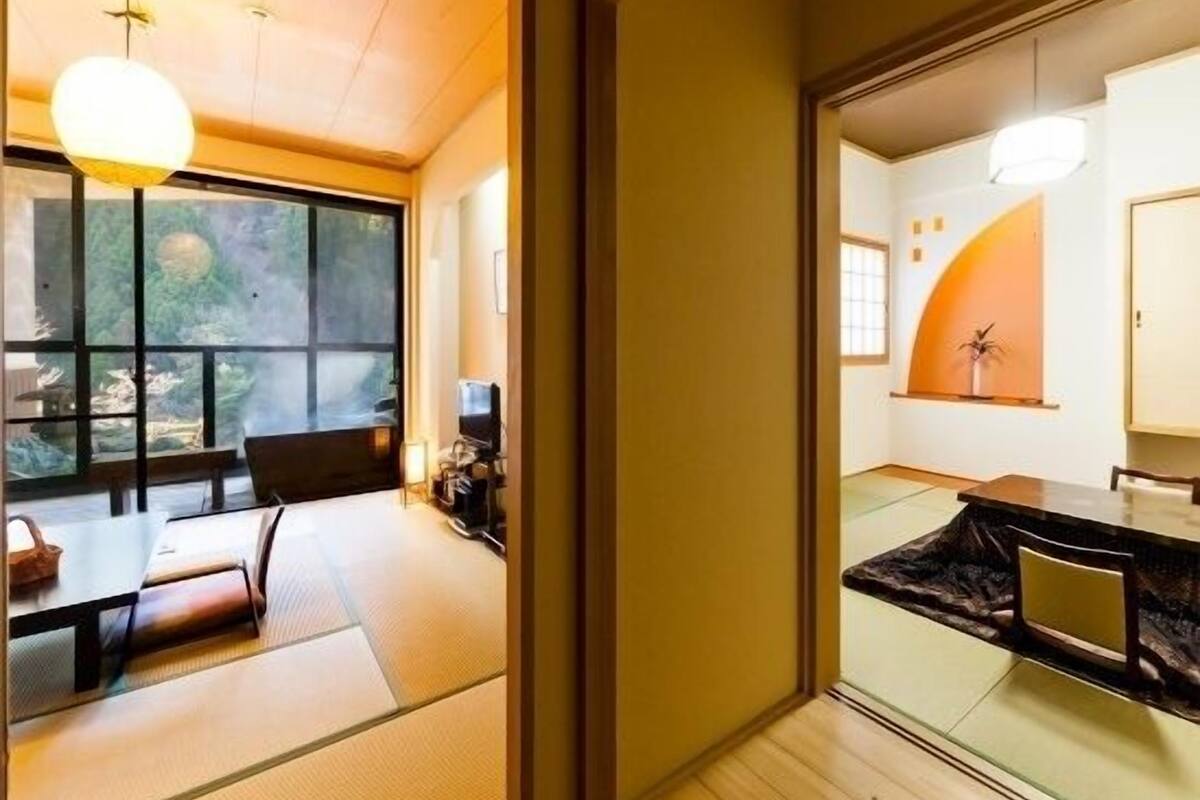 A traditional Japanese room with tatami flooring, a low table, and a sliding door leading to another room.