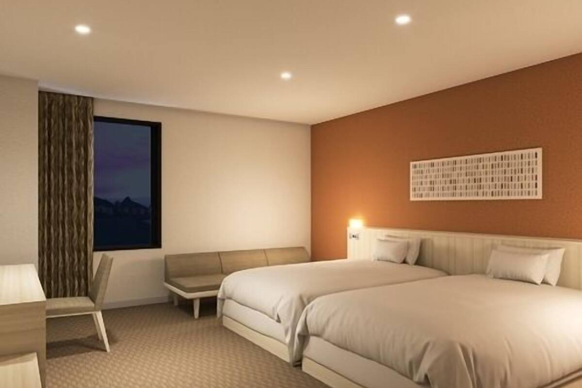 Habitación de hotel moderna con una cama grande, un escritorio, una silla y vistas a las montañas.