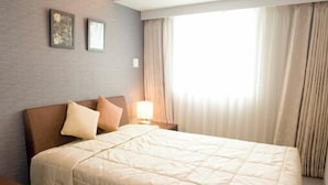 Une chambre d’hôtel avec un lit, une table de chevet, une lampe et une fenêtre avec des rideaux.