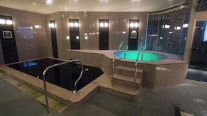 Une piscine avec des marches permettant d’y accéder, entourée de murs dotés d’un éclairage intégré.