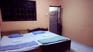 A single bed with a wooden frame, a window with a decorative grille, and a door with a glass panel. - Wooden Paracosm & Resort (Thissamaharama)