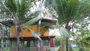 A two-story house with a balcony, surrounded by palm trees and greenery. - Wooden Paracosm & Resort (Thissamaharama)