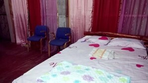 A bedroom with a bed, two blue chairs, and a wooden headboard. - Wooden Paracosm & Resort (Thissamaharama)