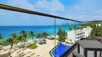 Un balcón con vista a la playa y a una piscina.