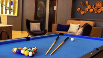 A pool table with billiard balls and cues, a sofa with cushions, and a wall with decorative wooden plates.