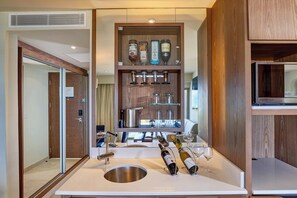 A modern bathroom with a large mirror, a sink, and a built-in wine cooler with bottles and glasses.