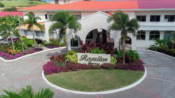 En hotellentrén med en skylt som visar texten ”Royalton Grenada”, omgiven av välskötta trädgårdar och palmer.