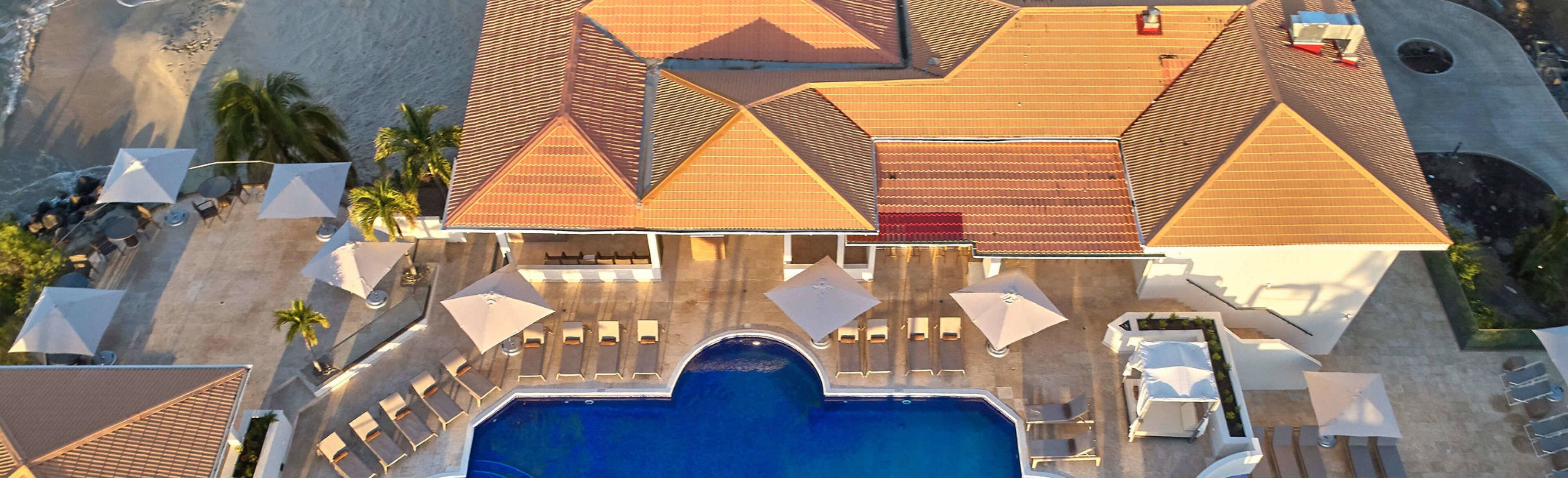 Vista aérea de un resort con piscina, tumbonas y zona de playa.