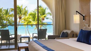 Une chambre d’hôtel avec un grand lit, une vue sur l’océan et un balcon équipé de chaises et d’une table.