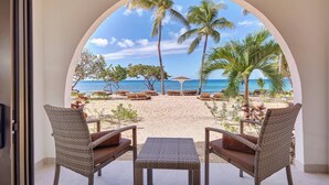 Une vue sur la plage, encadrée par une porte en arc, avec des meubles en osier et une petite table.