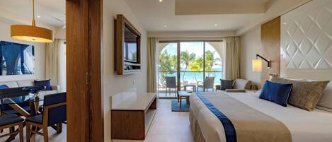 A hotel room with a bed, a desk, a chair, a TV, and a view of the ocean.