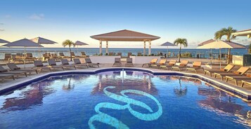 Una piscina al aire libre, sombrillas, sillones reclinables de piscina