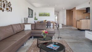 Ein modernes Wohnzimmer mit einer braunen Ledersofa, einem Essbereich mit Holztisch und einer Küche mit Holzausstattung.