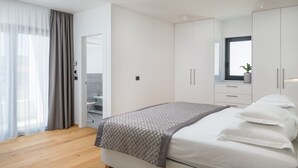 Ein modernes Schlafzimmer mit einem Bett, einem Kleiderschrank und einem durch eine offene Tür erreichbaren Badezimmer.