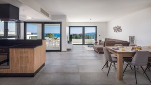 Eine moderne Wohnung mit Küche, Essbereich und einem Balkon mit Meerblick.