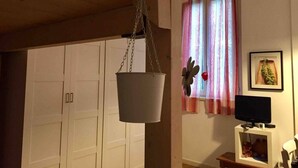 A room with a white wardrobe, a hanging plant, a television, and a window with curtains. - Tree House Along Canal Naviglio Grande (Milano)