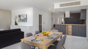 Un espace repas moderne avec une table en bois dressée pour quatre personnes, entourée de chaises à revêtement gris.